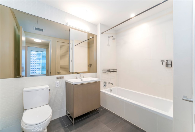 Spacious bathroom with acrylic soaking tub with tile shower surround and porcelain tile floor